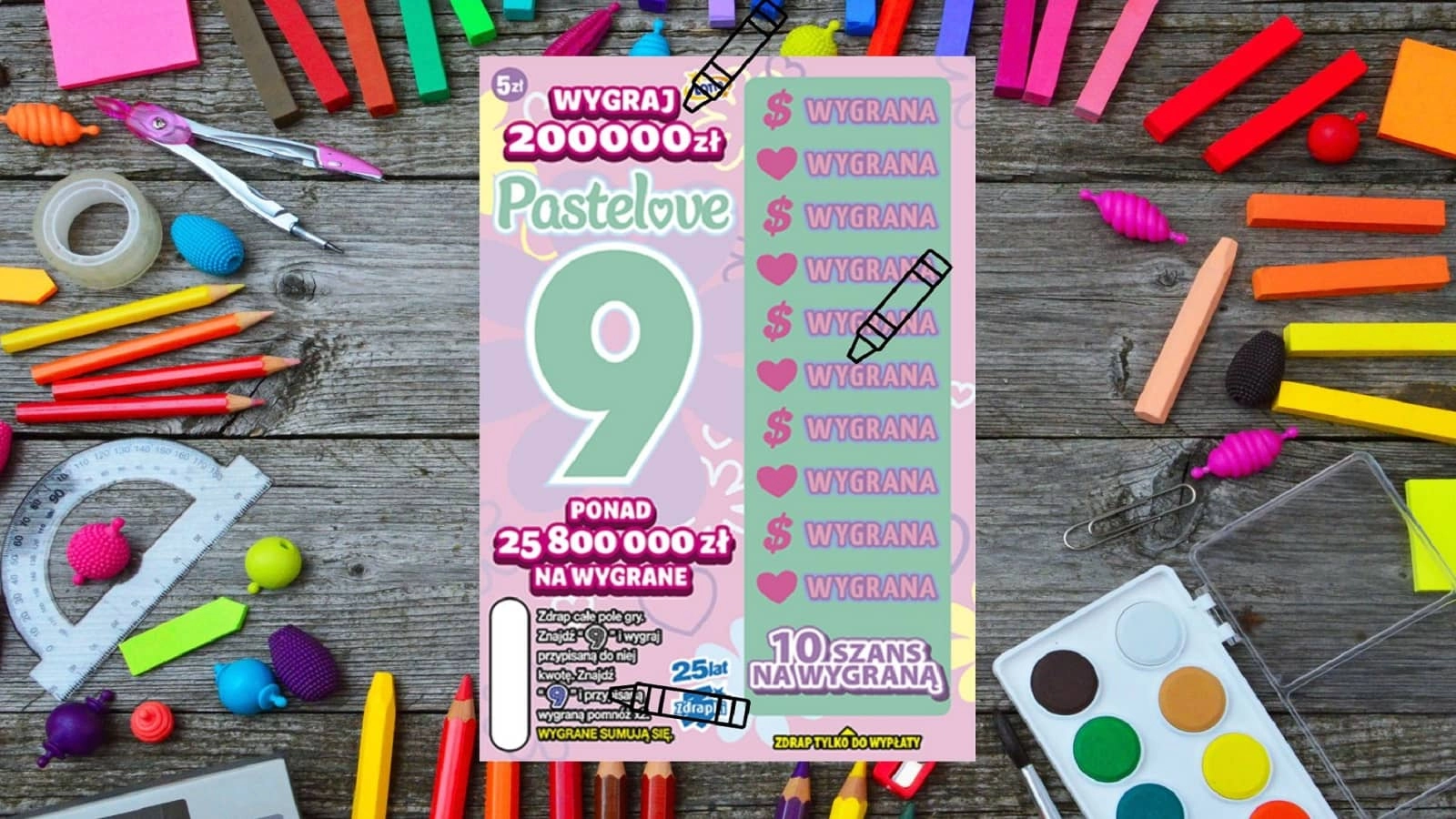 zdrapka Lotto Pastelove 9 leżąca na przyborach do malowania, kredkach, flamastrach