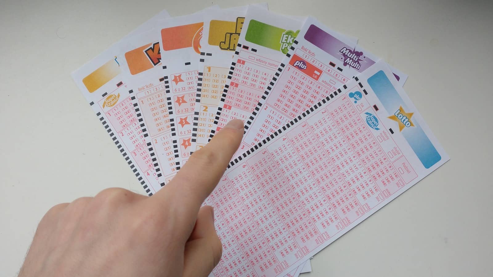 dłoń wskazująca jeden z kuponów gier liczbowych