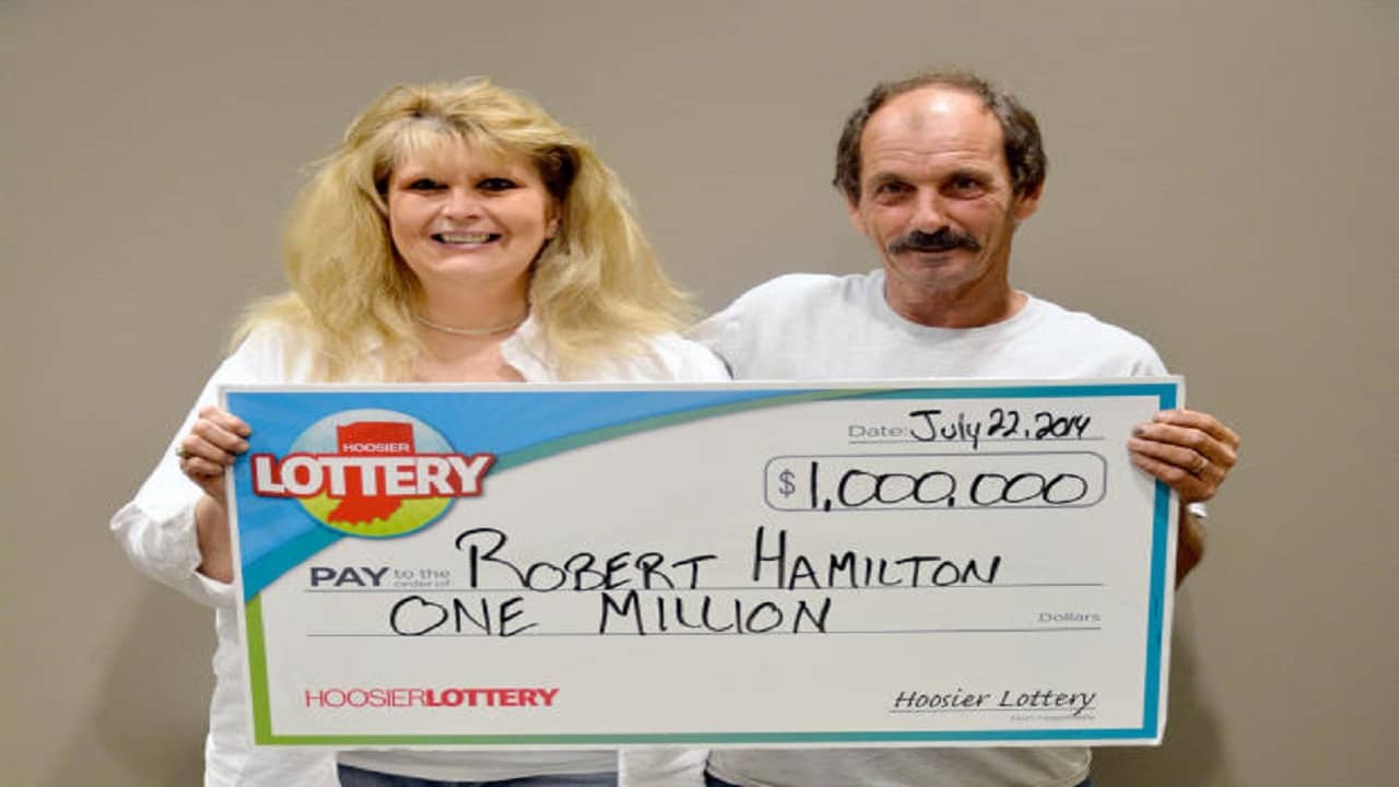 Robert Hamilton z żoną trzymający duży wygrywający czek Lotto