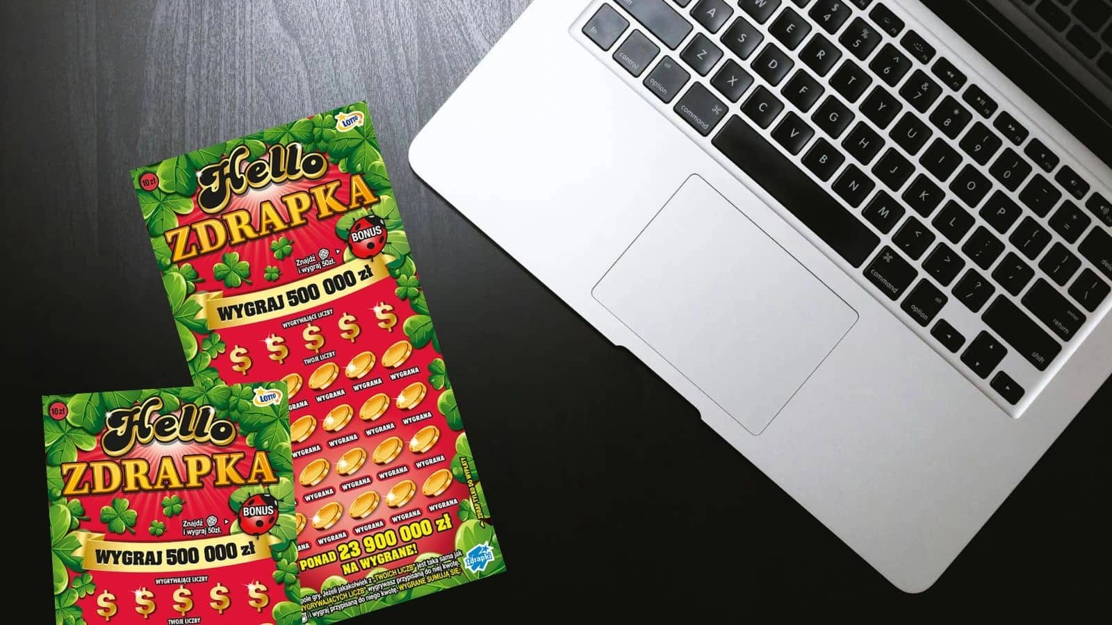 dwie sztuki zdrapki lotto hello zdrapka, fragment komputera przenośnego z klawiaturą na czarnym drewnopodobnym blacie stołu