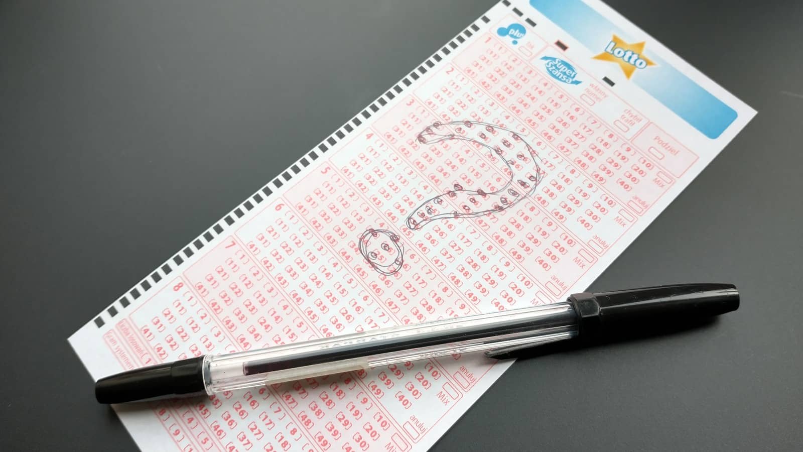 długopis, kupon Lotto na którym zaznaczono schemat znaku zapytania