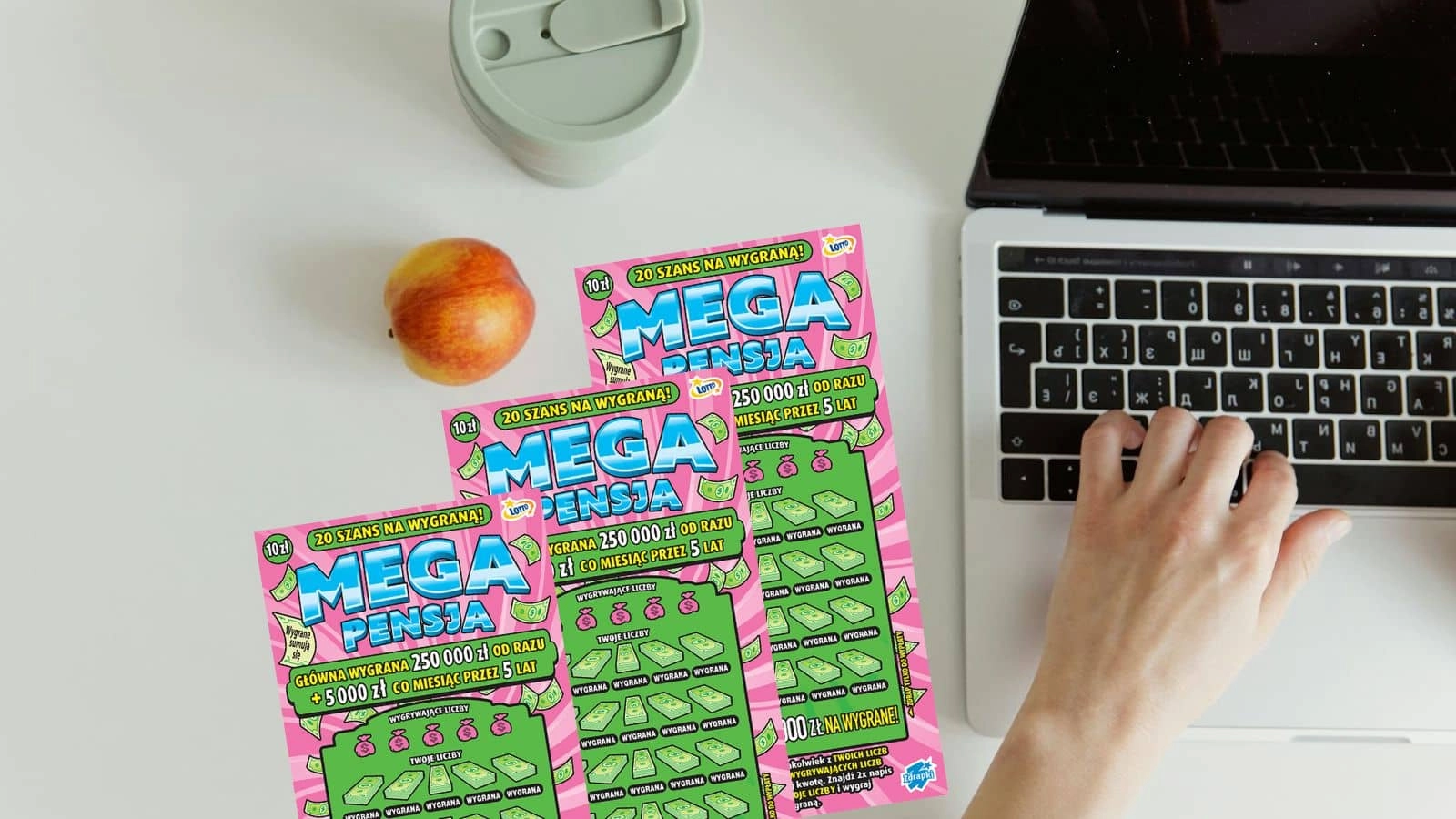 różowe odmiany zdrapek Mega Pensja, jabłko, termos, dłoń na klawiaturze laptopa