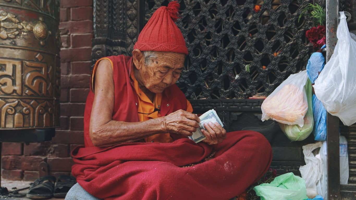 mnich w czerwonym ubraniu przelicza plik dolarów