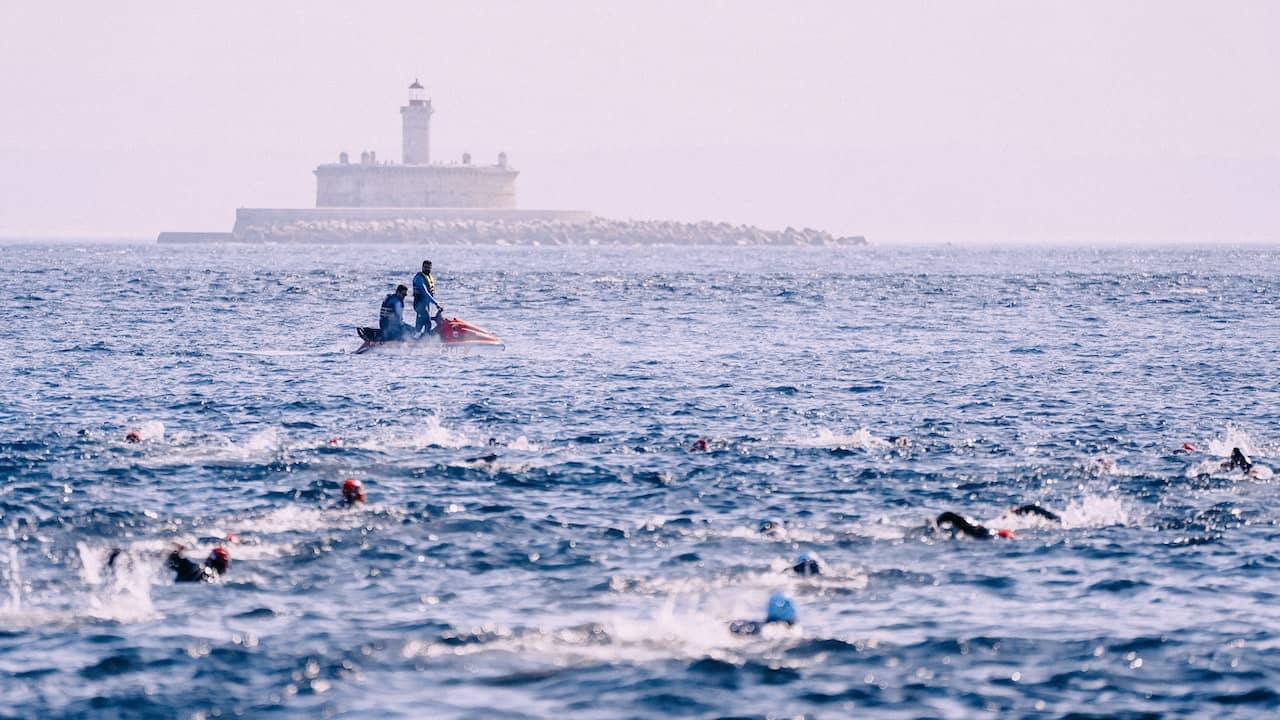 kilkunastu zawodników płynie w morzu pokonujac trasę thriatlonu