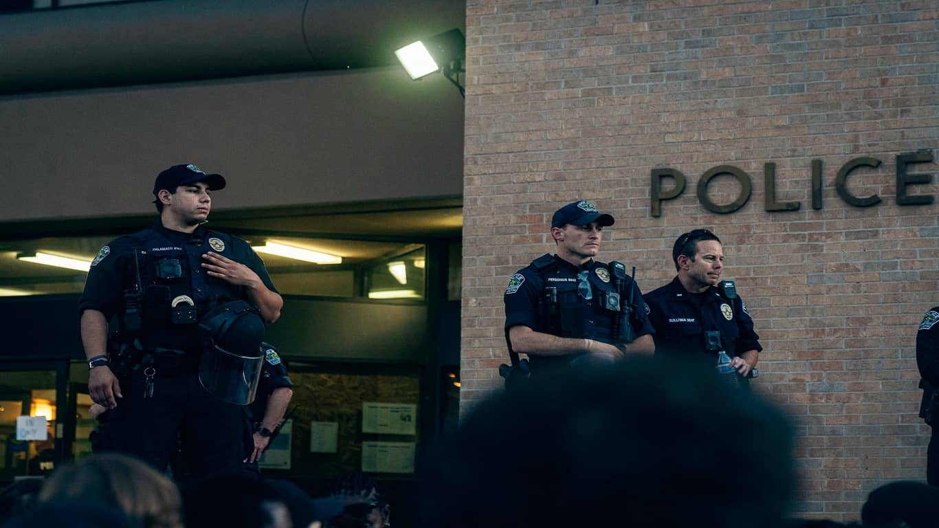 trójka policjantów stojąca przed budynkiem komendy