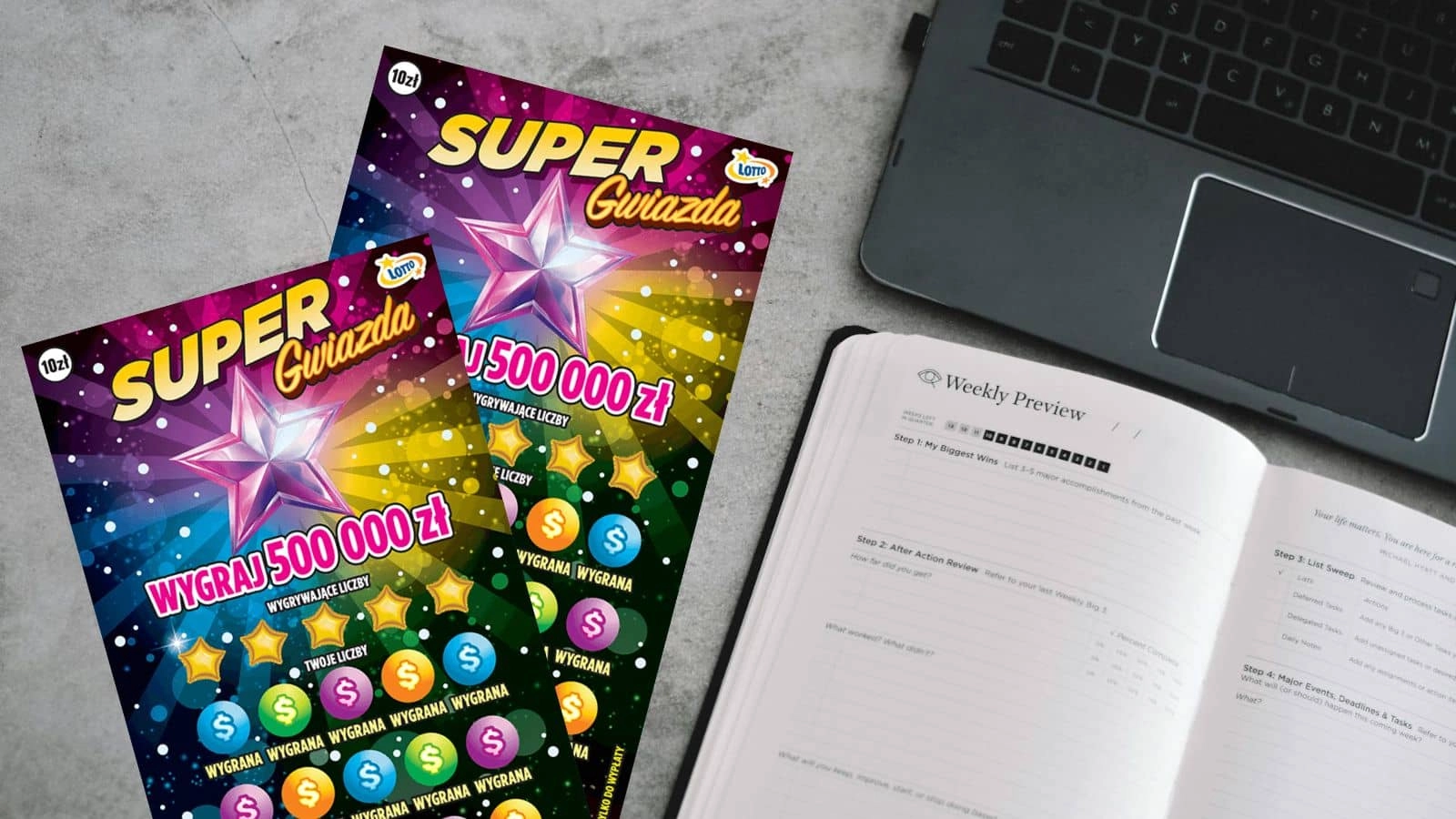 dwie sztuki zdrapki Lotto Super Gwiazda, planer, laptop na szarym marmurowym blacie stołu