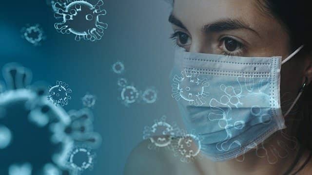 twarz kobiety w maseczce medycznej oraz model wirusa w powietrzu