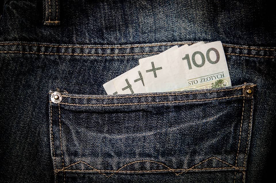 trzy banknoty o nominale 100 zł włożone do tylnej kieszeni spodni dżinsowych